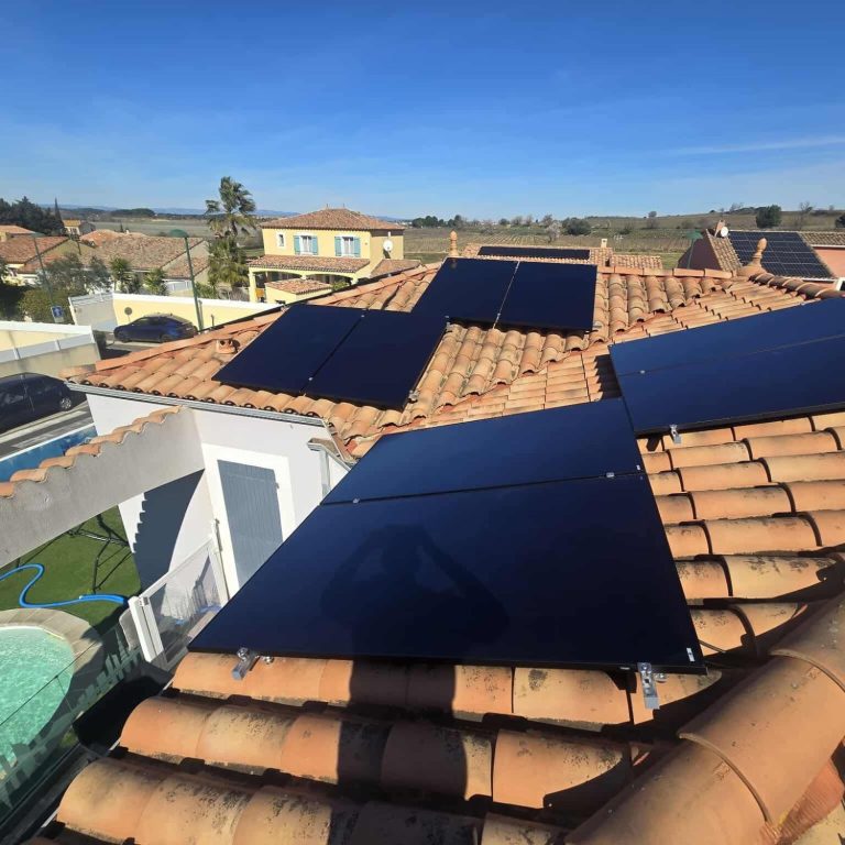Panneaux solaires installés sur un toit de tuiles, en arrière-plan des champs.