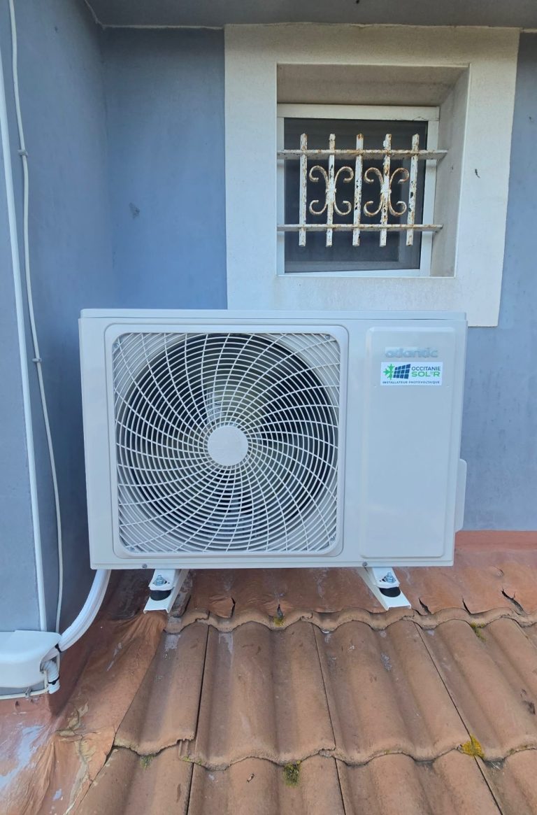 Panneaux solaires installés sur un toit de tuiles, en arrière-plan des champs.