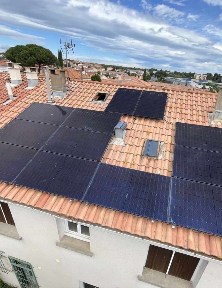 Panneaux solaires installés sur un toit de tuiles, en arrière-plan des champs.